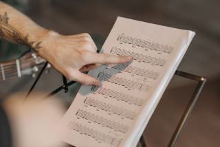 Tablature et partition côte à côte Manche de guitare posé sur une feuille de musique manuscrite